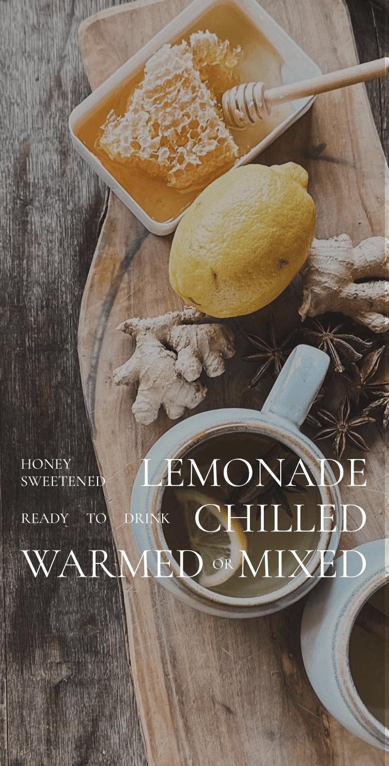 A rustic wood board holding a dish of honeycomb, a lemon, pieces of ginger and anise seed, and two mugs of hot lemonade. Text overlay reads Honey sweetened lemonade, ready to drink chilled, warmed, or mixed.